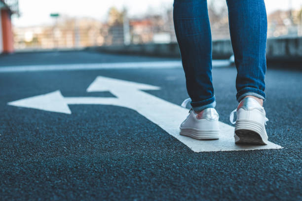 Female legs wearing jeans and white sneakers.